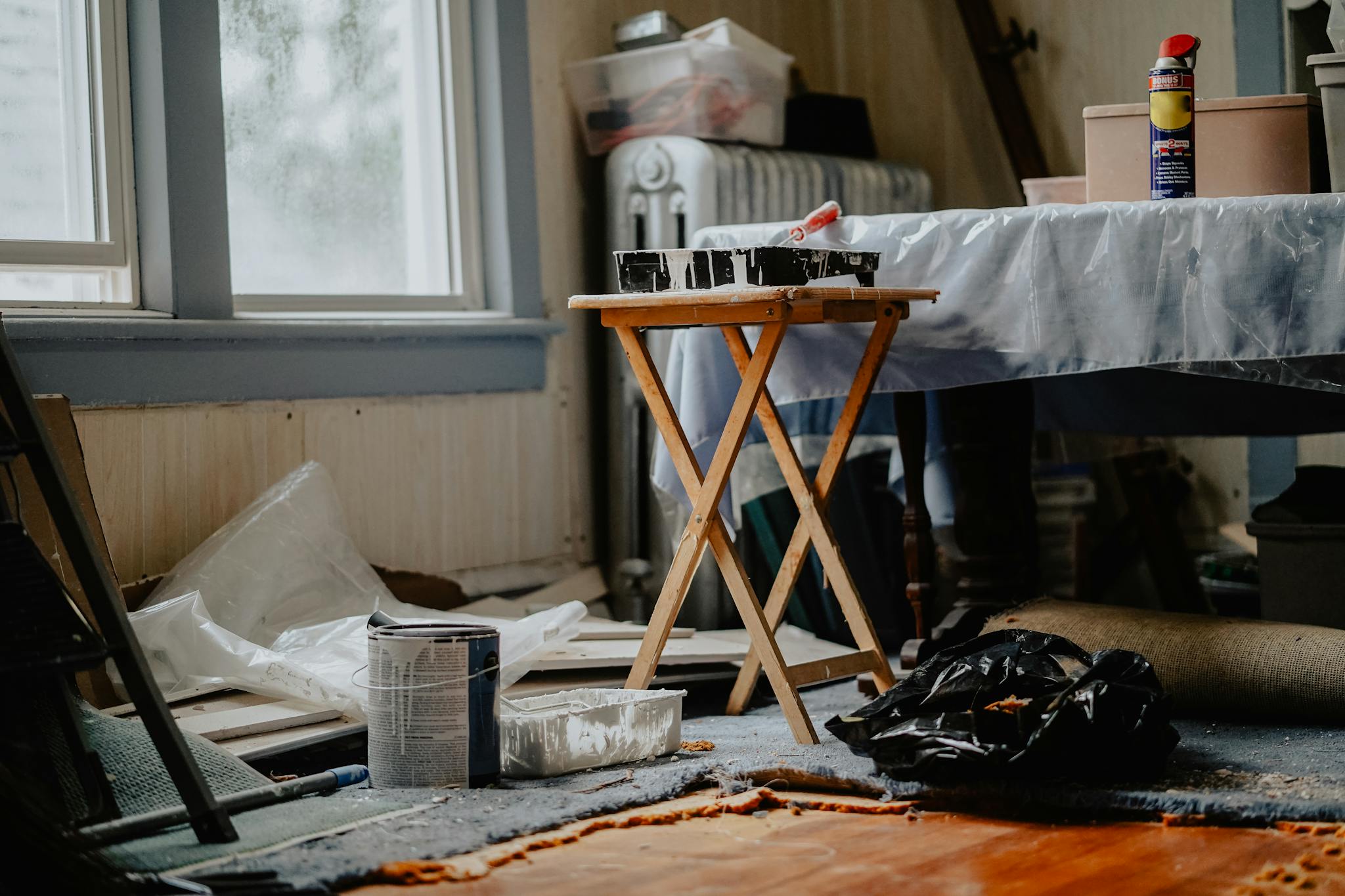 Interior view of a home renovation with paint supplies on a wooden table.